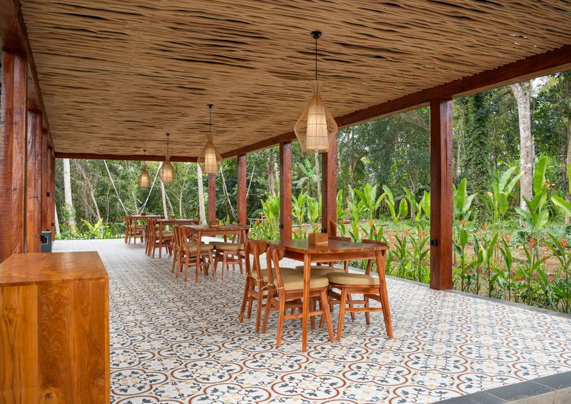 The long terrace, tables running its length beside the banana grove